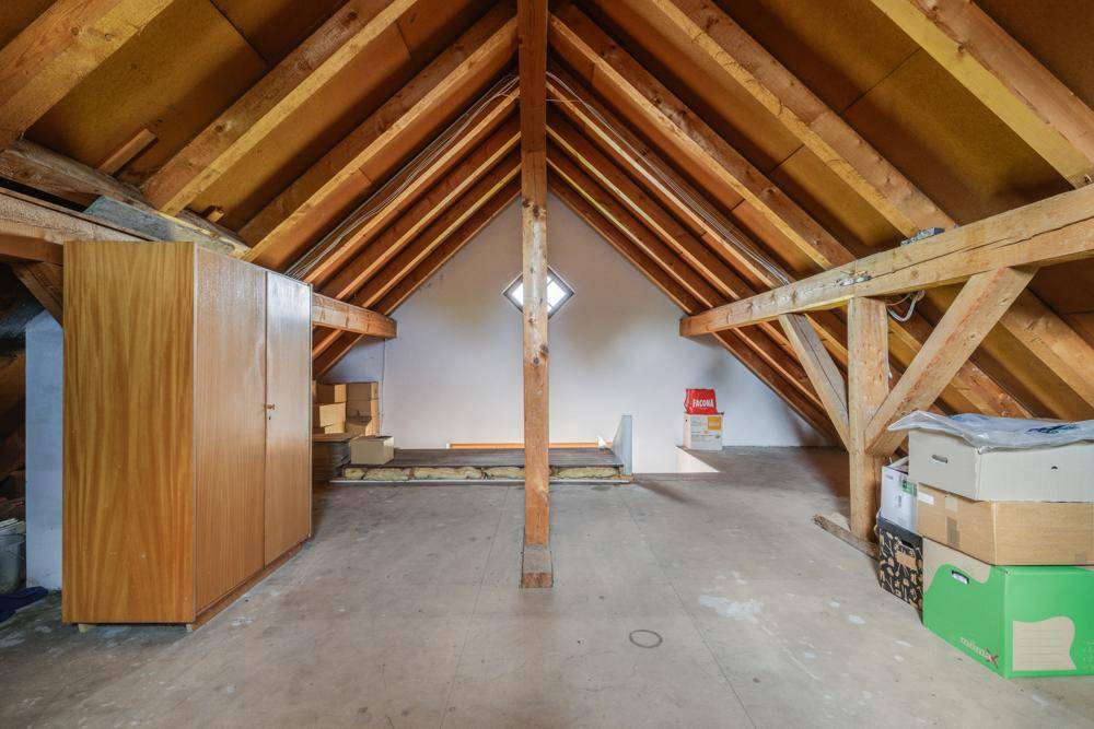 Geräumiger Dachboden mit sichtbaren Holzbalken, Dachschräge und Stauraum.