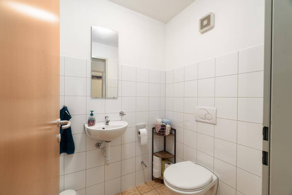 Separates WC mit Waschbecken, Toilette und Wandfliesen.