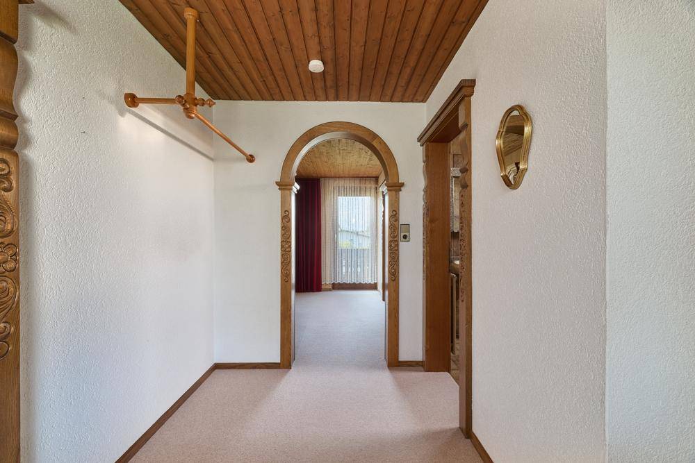Flur mit Holzdecke, Teppichboden und einem Rundbogen, der zu einem weiteren Raum führt.