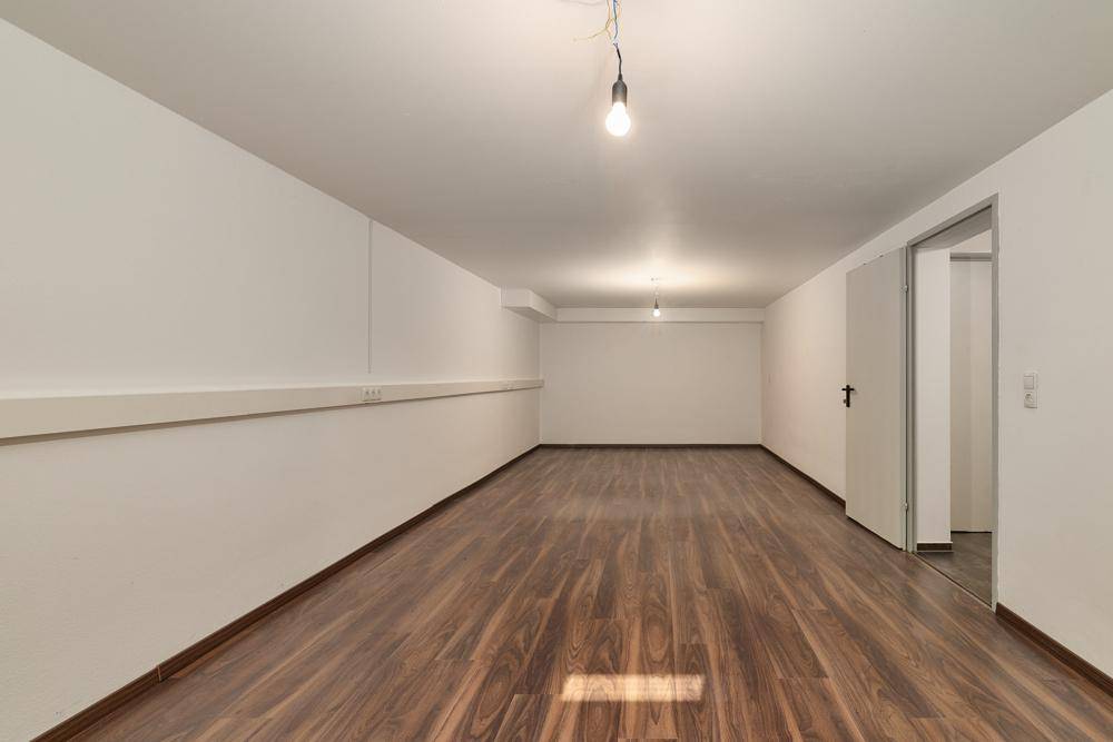 Geräumiger Kellerraum mit Laminatboden und weiß gestrichenen Wänden.