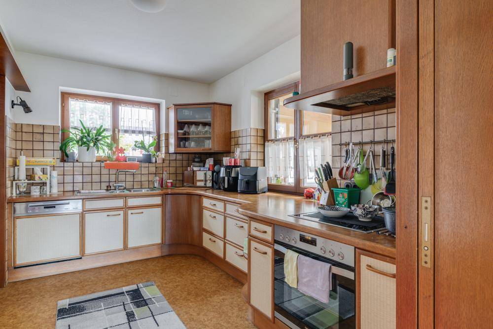 Traditionelle Küche mit Holzfronten, gefliesten Wänden und integrierten Geräten.
