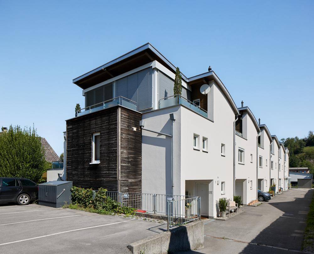 Moderne Reihenhäuser mit unterschiedlichen Fassadenmaterialien und Parkplätzen.