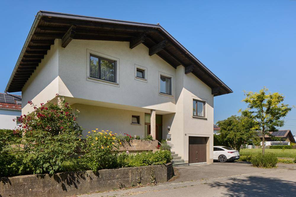 Ansicht des Einfamilienhauses von der Straße mit Garage und Vorgarten.