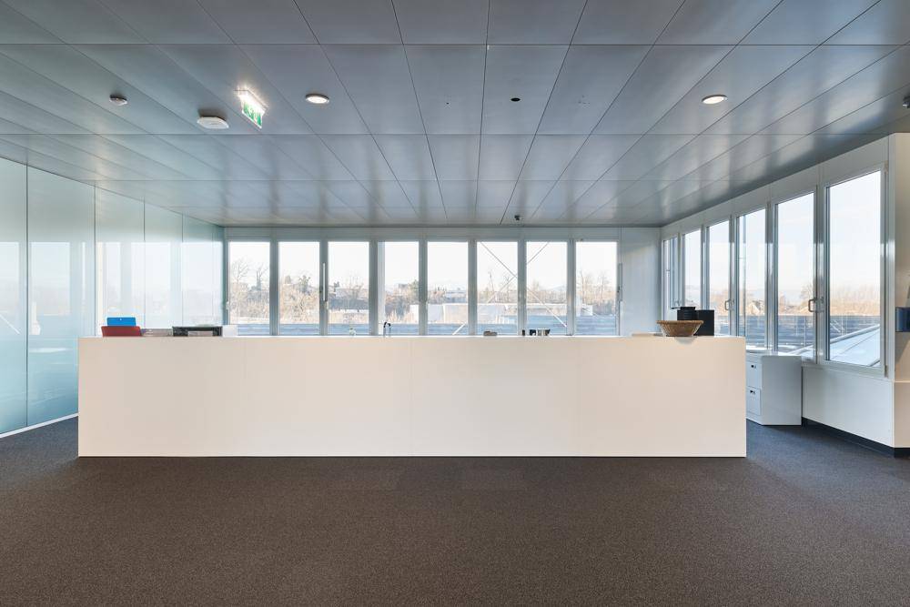 Großer Empfangstresen in einem hellen Raum mit Teppichboden und weitem Ausblick durch die Fensterfront.