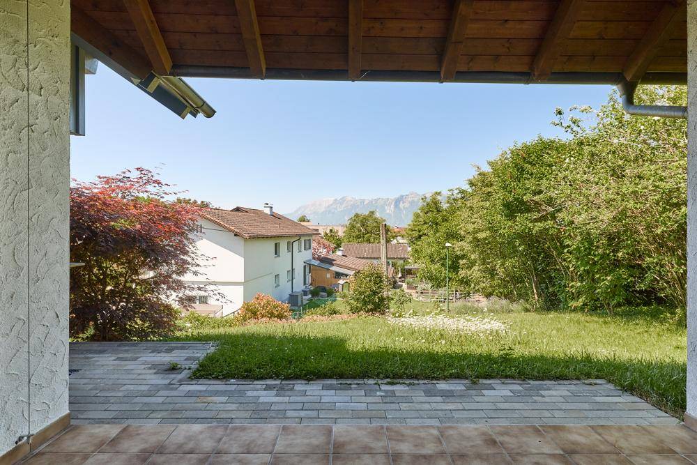 Blick von der Terrasse auf die umliegende Landschaft und die Berge im Hintergrund.