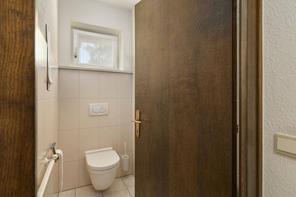 Helles Gäste-WC mit Toilette, kleinem Waschbecken und Fenster.