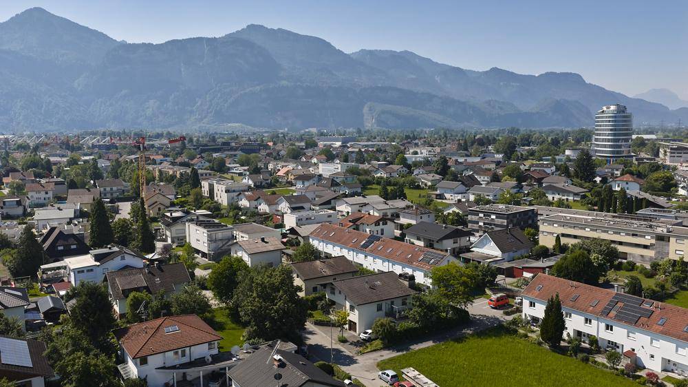 Panoramablick über die Stadt mit Wohngebieten und majestätischen Bergen im Hintergrund.