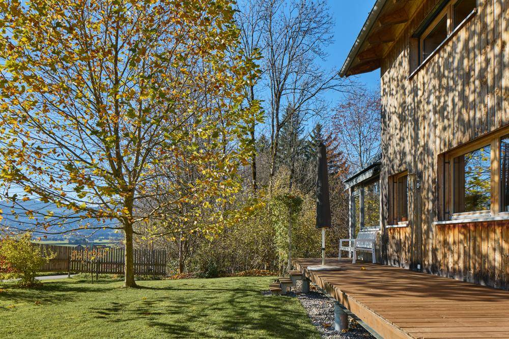 Große Holzterrasse mit Gartenmöbeln und weitem Blick in die Landschaft.