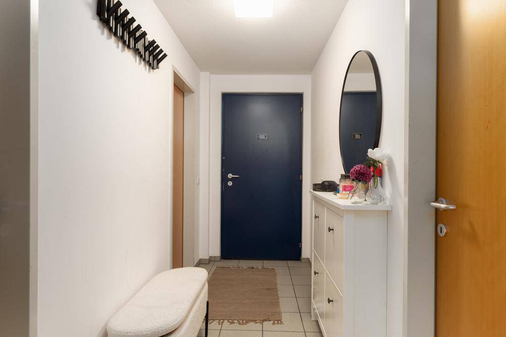 Eingangsbereich mit Fliesenboden, Garderobe, Spiegel und Schuhschrank.