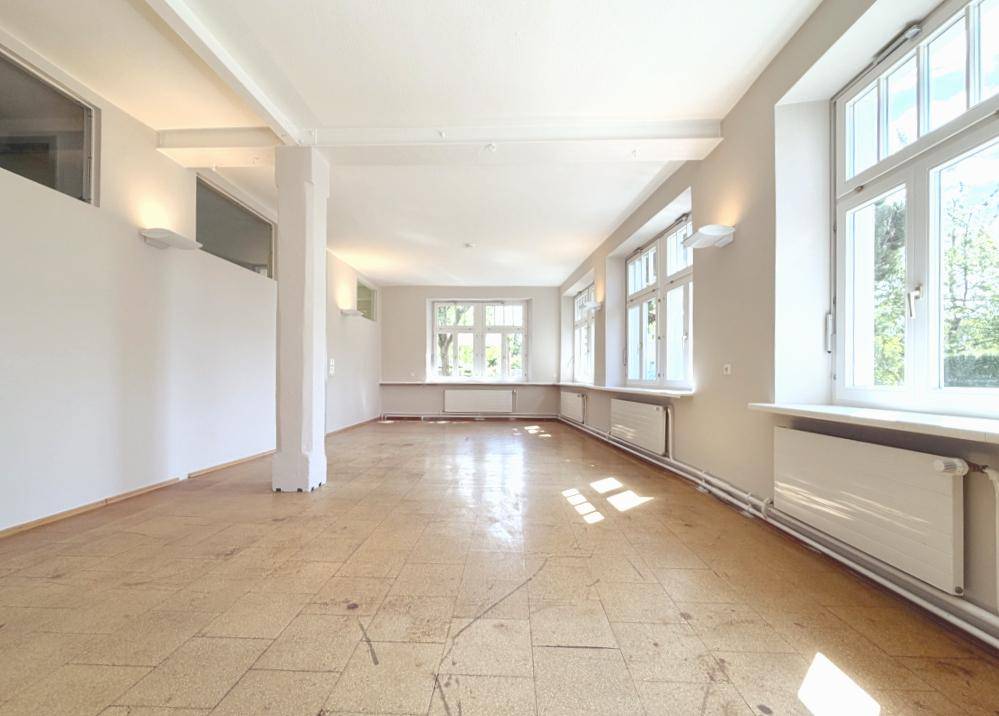 Geräumiger, heller Raum mit vielen Fenstern und Holzboden.