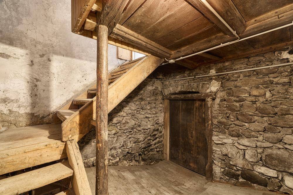 Kellerbereich mit rustikalen Holztreppen und Natursteinmauern, unfertiger Zustand.