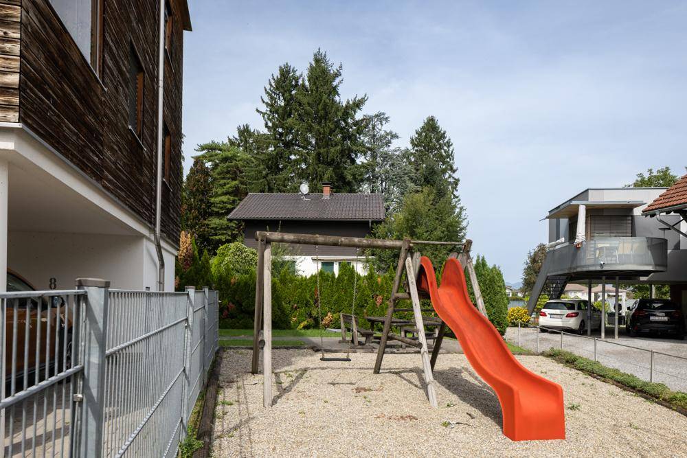 Kinderspielplatz mit Rutsche und Schaukeln neben dem Wohngebäude.