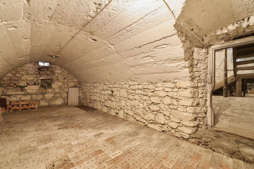 Rustikaler Gewölbekeller mit Steinmauern und Ziegelboden, ideal als Weinkeller.