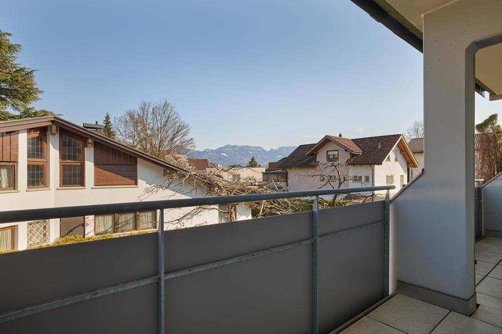 Balkon mit weitem Blick über die Dächer der Nachbarschaft bis zu den Bergen.