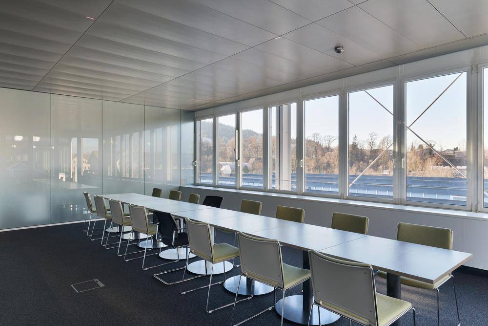 Heller Konferenzraum mit langem Tisch, modernen Stühlen und Panoramablick auf die Umgebung.