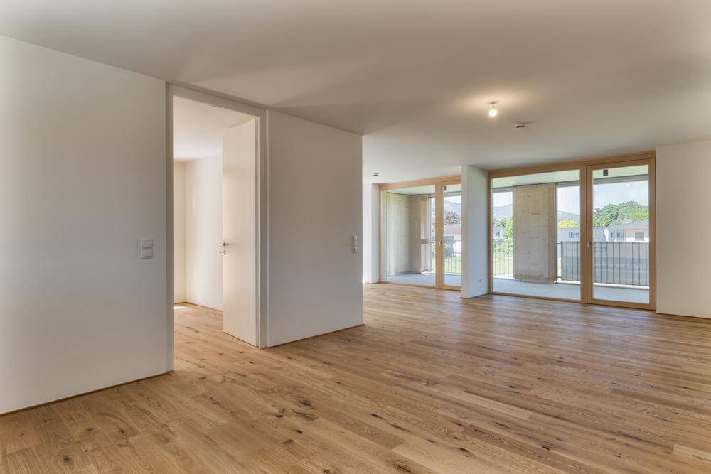 Geräumiger, heller Raum mit hellem Holzplankenboden und großen Glasfronten zum Außenbereich.