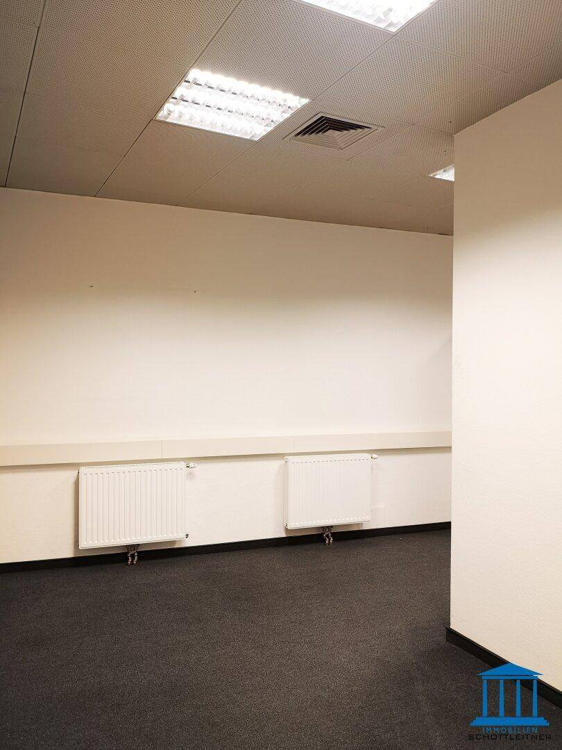 Bürofläche mit Teppichboden, mehreren Heizkörpern und abgehängter Decke, bietet vielseitige Nutzungsmöglichkeiten.