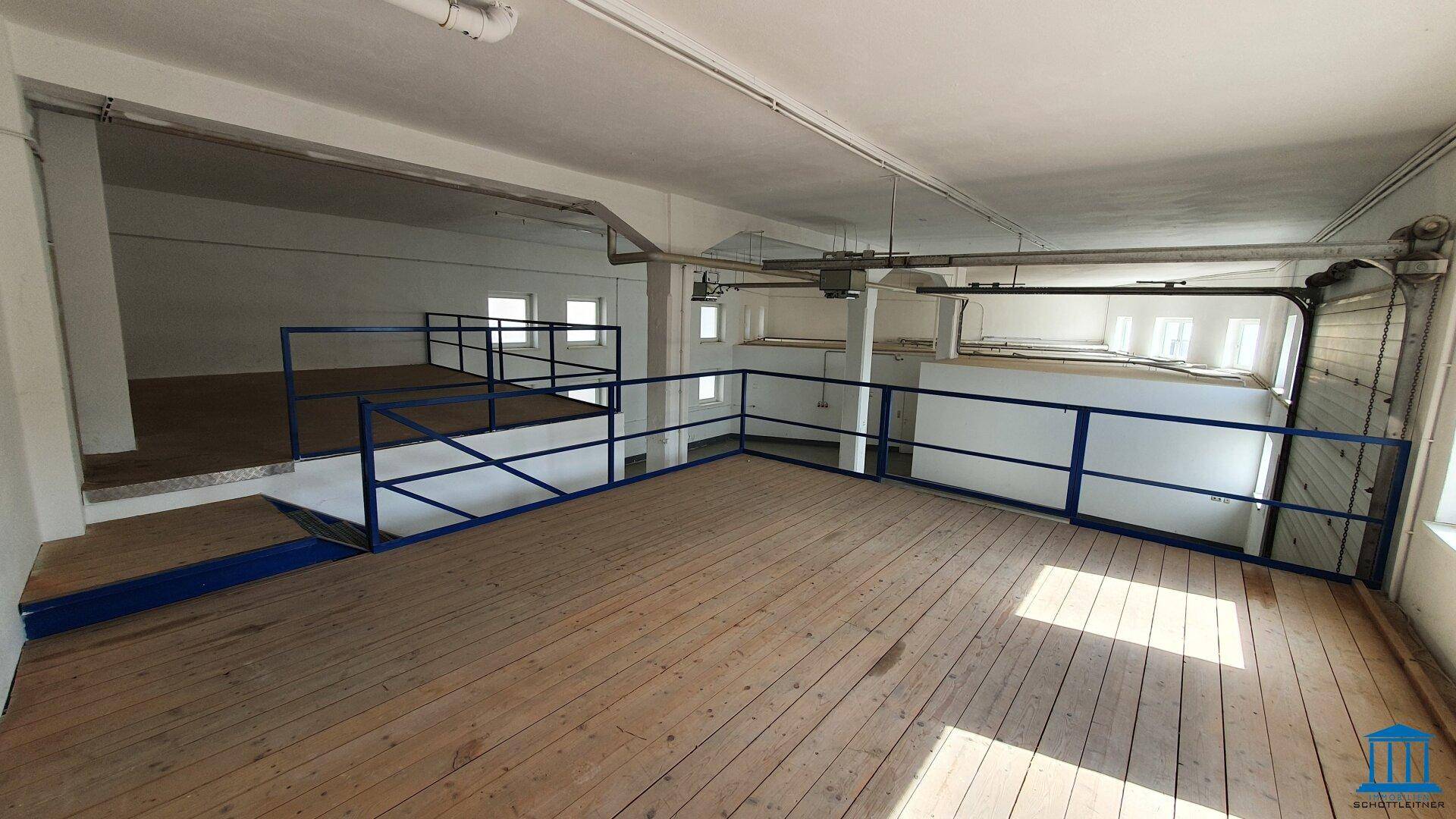 Mezzanine-Ebene mit Holzboden und blauen Geländern, bietet zusätzlichen Raum in der Halle.