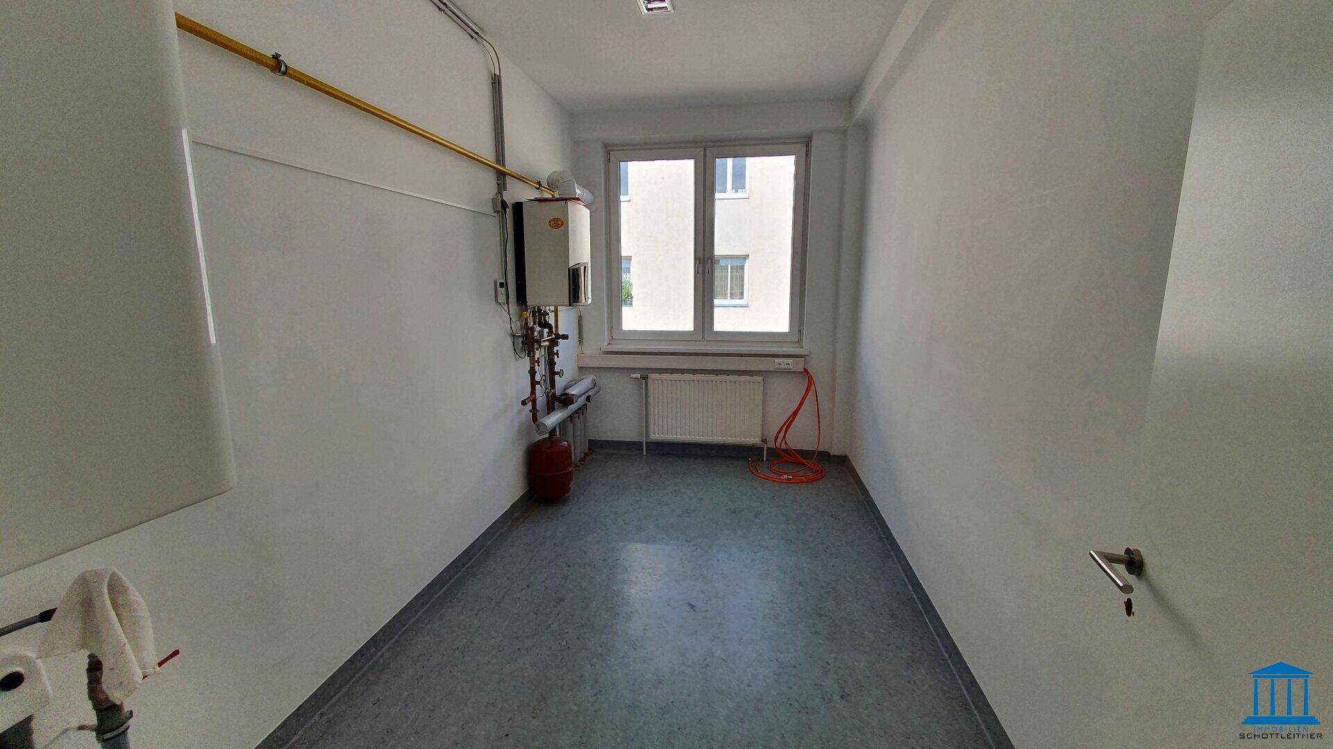 Funktionaler Hauswirtschaftsraum mit Heizungsanlage, Gasleitungen, Heizkörper und Fenster für natürliches Licht.