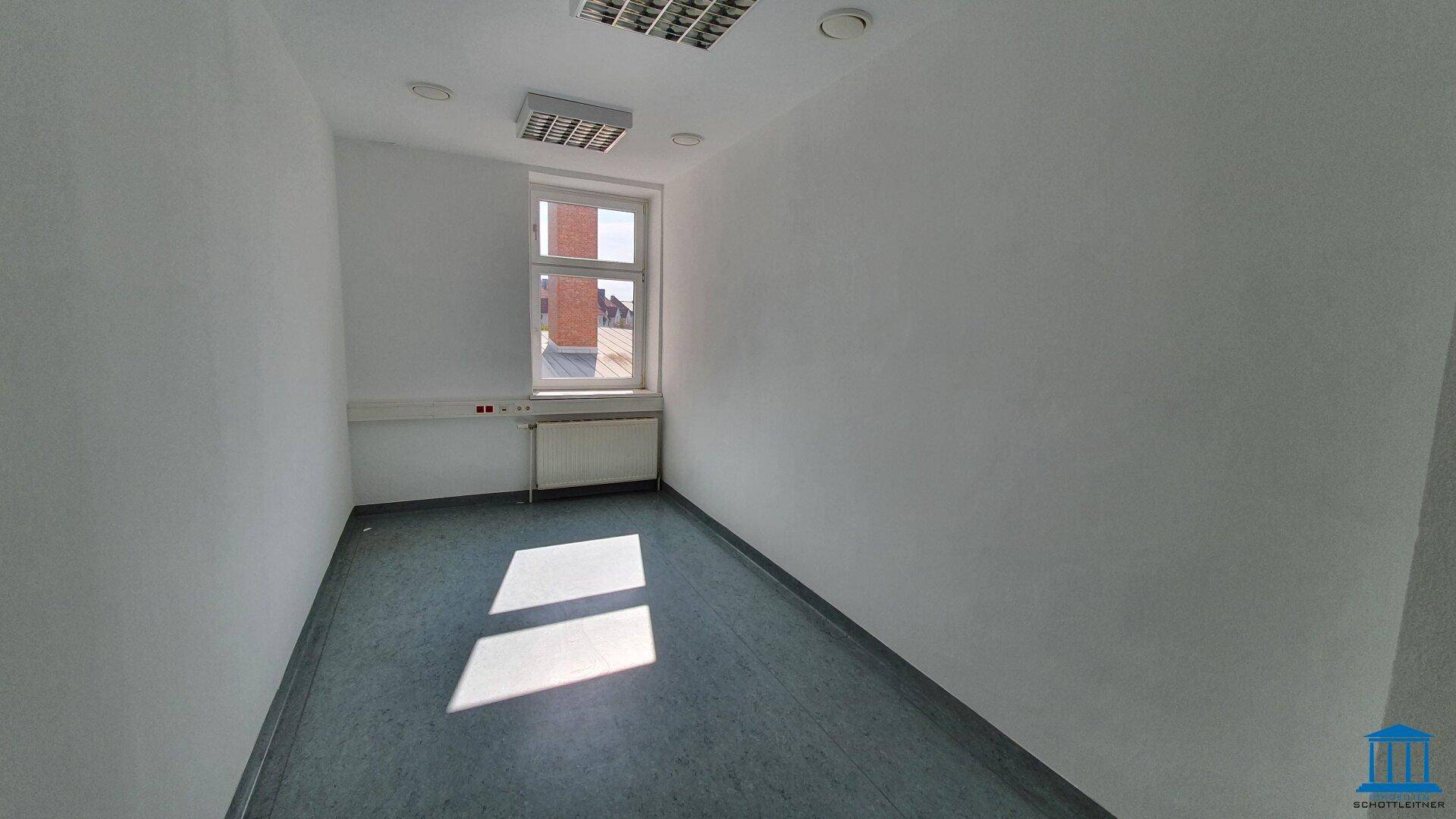Kleiner, heller Büroraum mit einem Fenster und grauem Boden, geeignet für Einzelbüro oder Besprechungen.