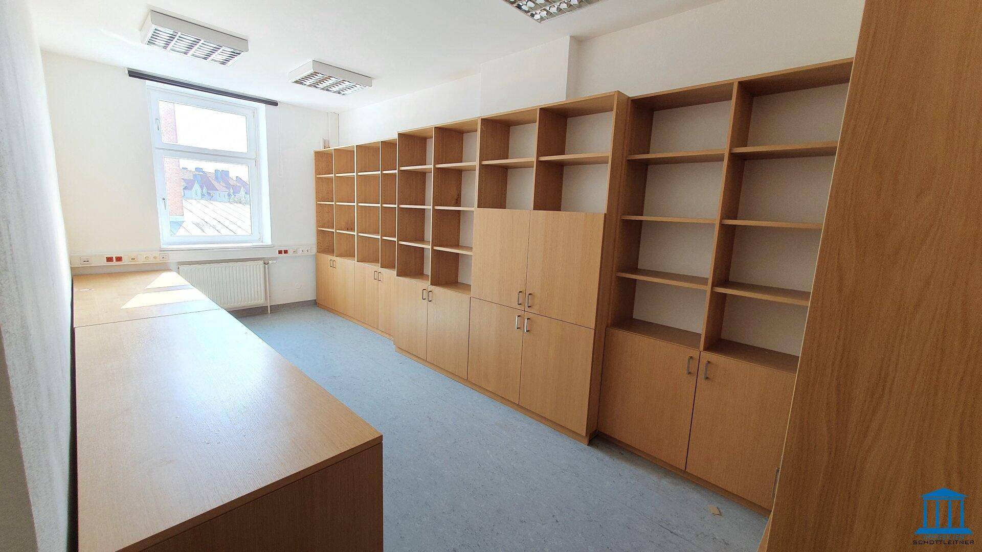 Büroraum mit eingebauten Holzregalen und einem Fenster, ideal für Archivierung oder Lagerung.