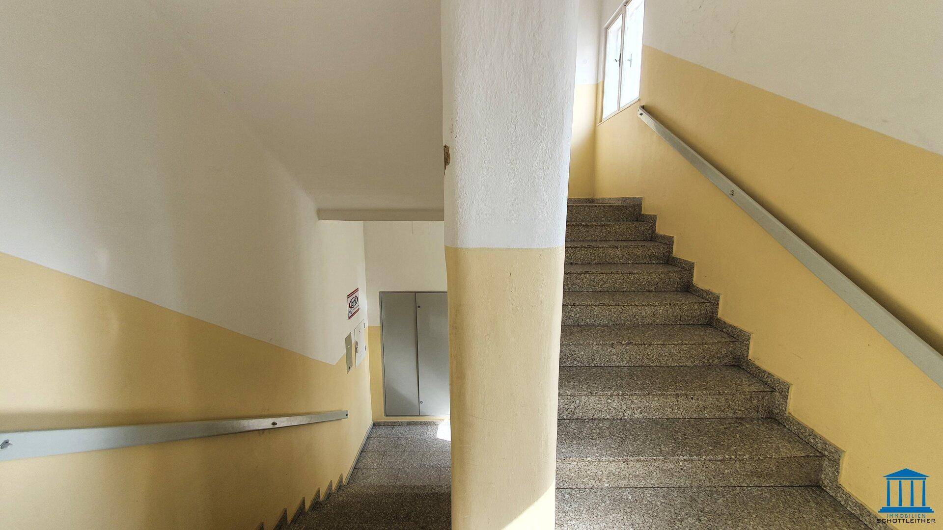Treppenhaus mit gelb gestrichenen Wänden und Granitstufen, führt zu den oberen Etagen.