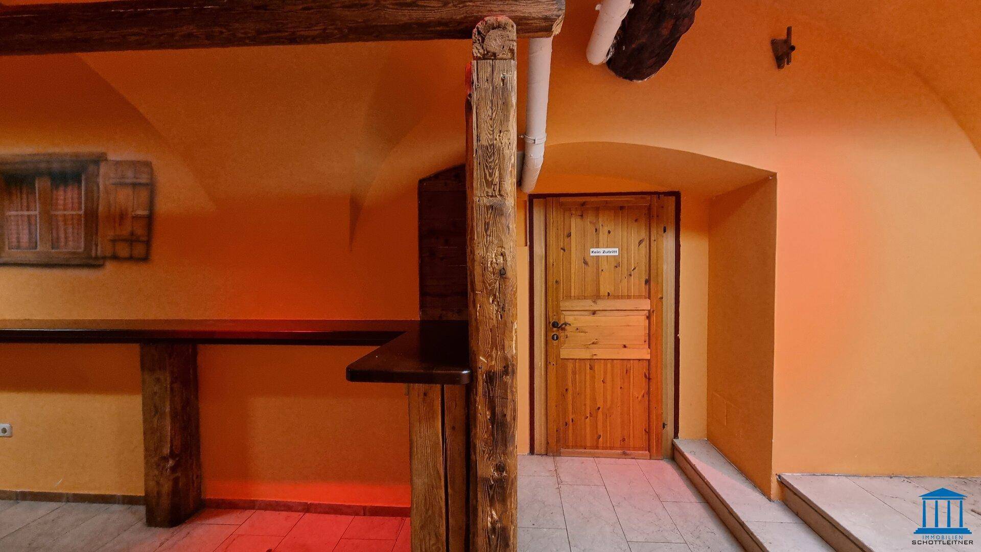 Rustikaler Barbereich mit Holzelementen, einer Holztür und gewölbten Decken.