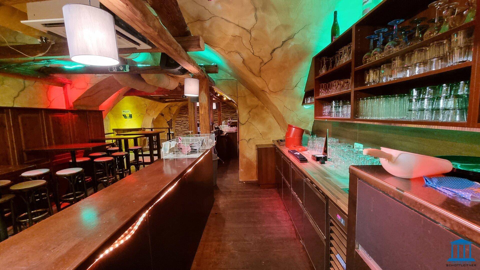 Thekenbereich mit Regalen voller Gläser und Flaschen, beleuchtet mit farbigem Licht.
