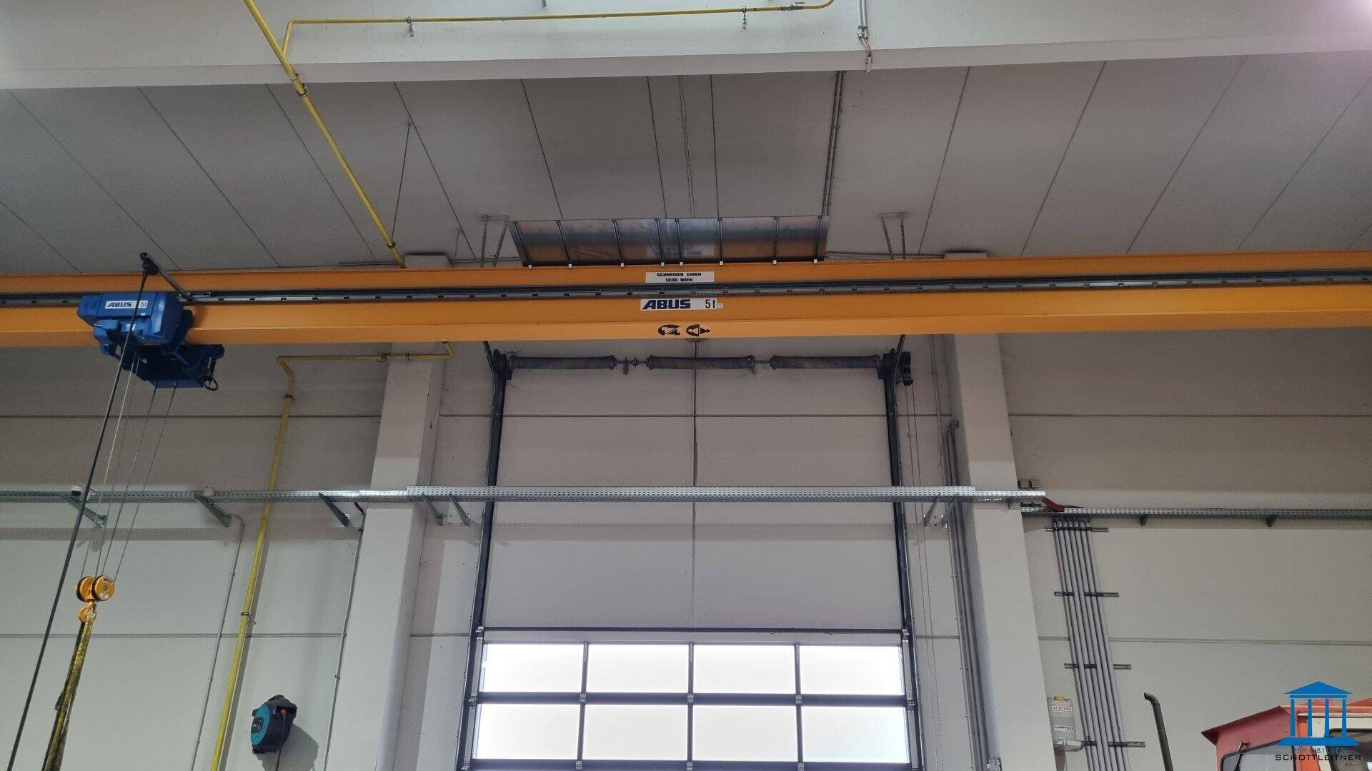 Industriedecke einer Lagerhalle mit Krananlage und großem Rolltor.