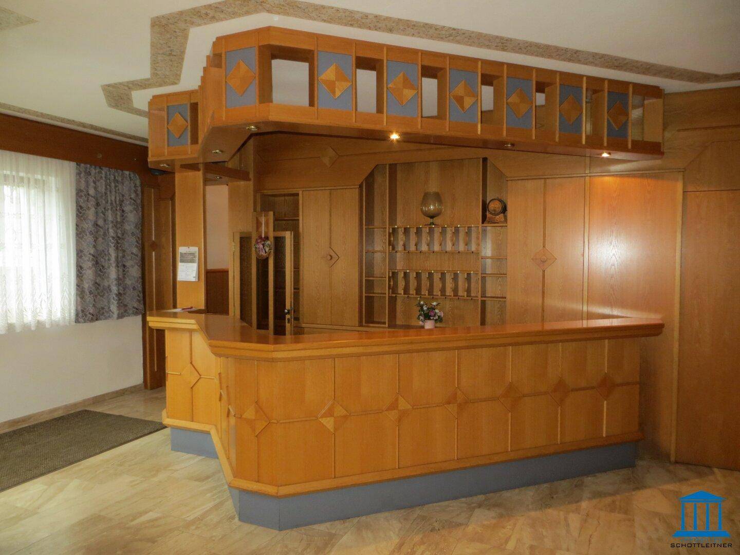 Holzvertäfelte Rezeption oder Bar mit traditionellem Design und gemustertem Deckenbereich.
