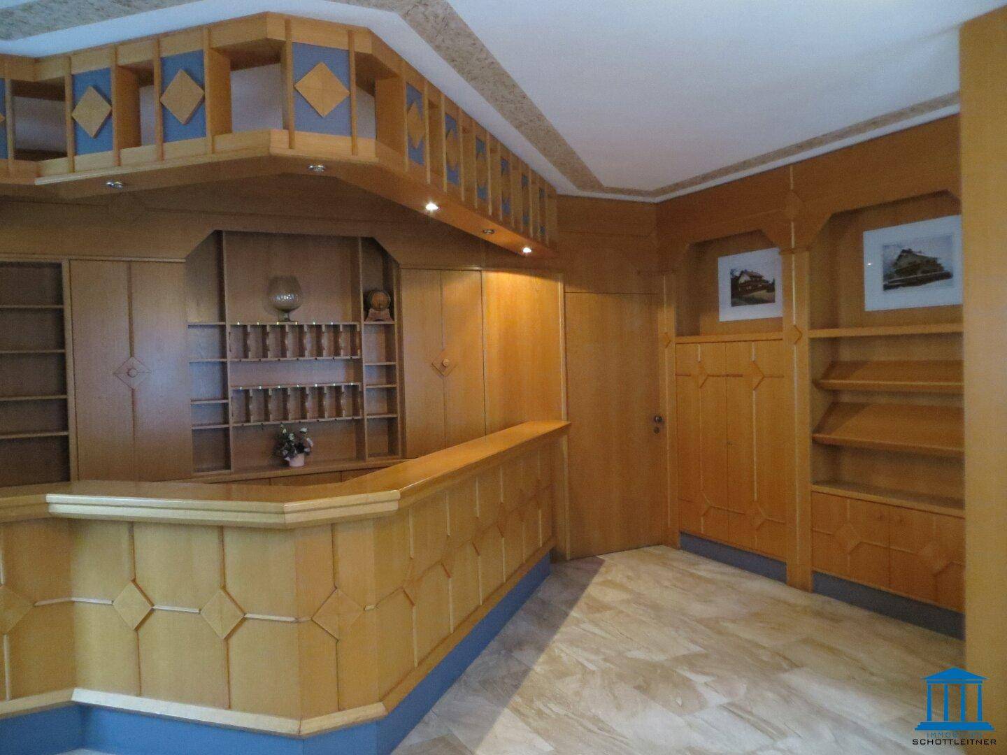 Traditioneller Empfangsbereich mit Holzvertäfelung, Regalen und Steinboden.