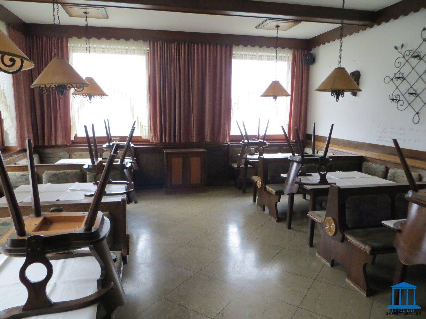 Gemütlicher Speisesaal mit traditionellen Holzbänken, Tischen und gefliestem Boden.