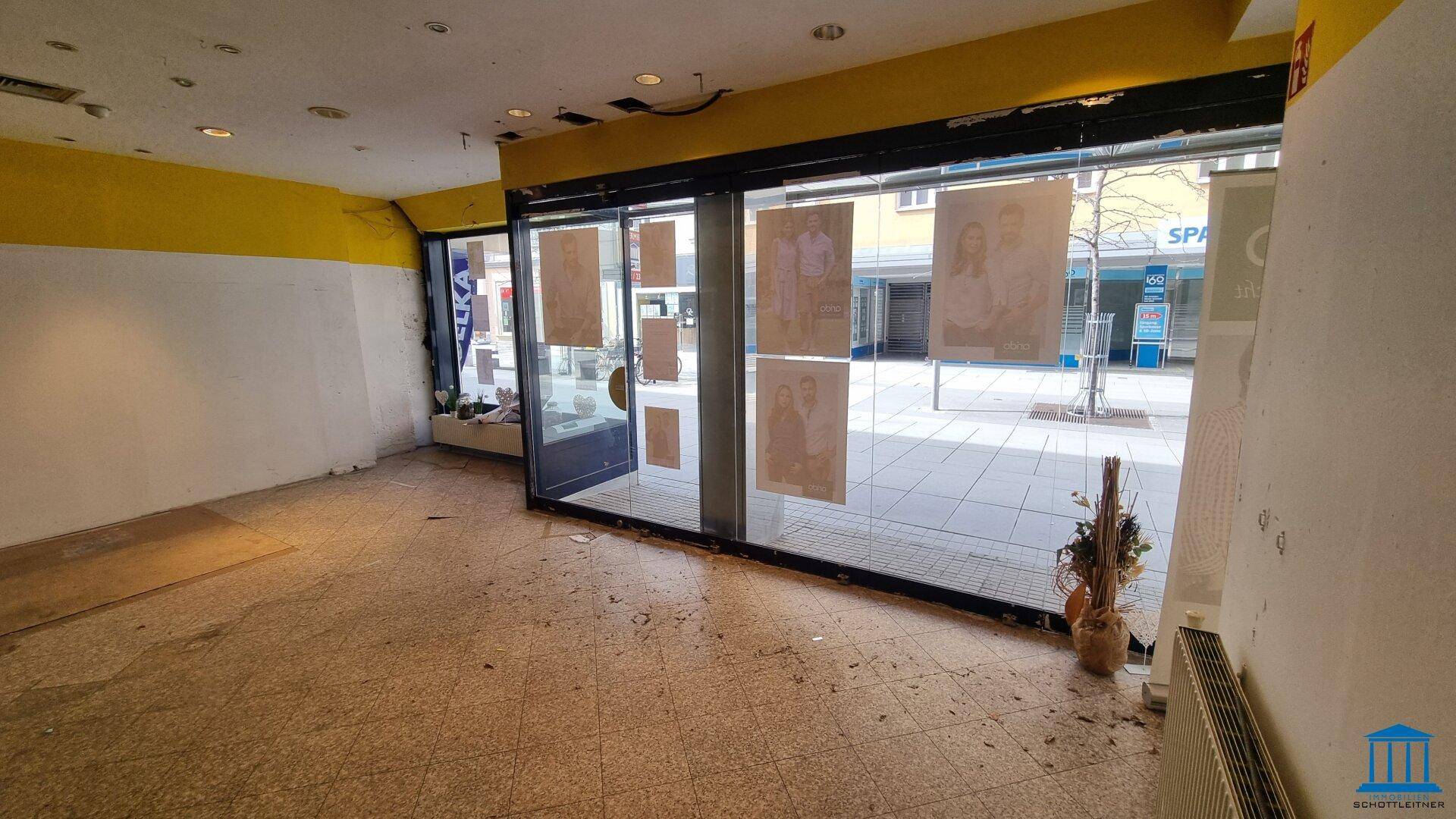 Geräumiger Ladenbereich mit großen Glasfronten zur Straße und einem hellen Fliesenboden.