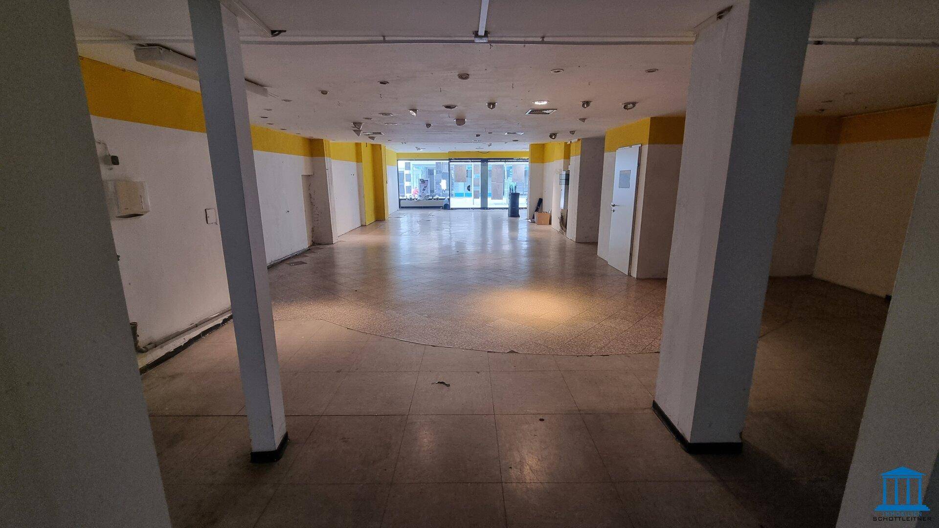 Offener Ladenraum mit Säulen und Fliesenboden, der viel Gestaltungsfreiheit bietet.