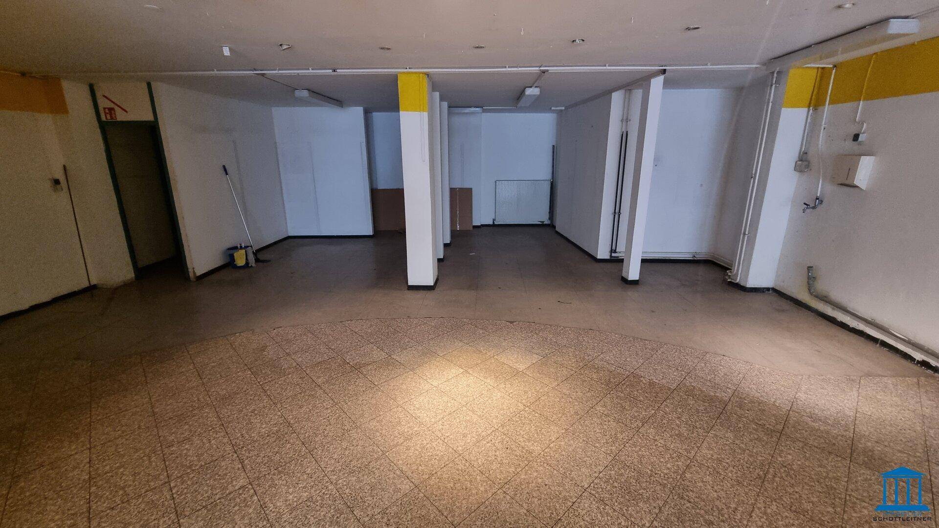 Hinterer Bereich des Ladenlokals mit Fliesenboden und vorbereiteten Wänden für den Ausbau.