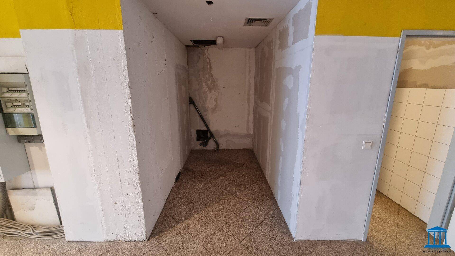 Unfertiger Raum mit sichtbaren Installationen und Fliesenboden, bereit für den weiteren Ausbau.