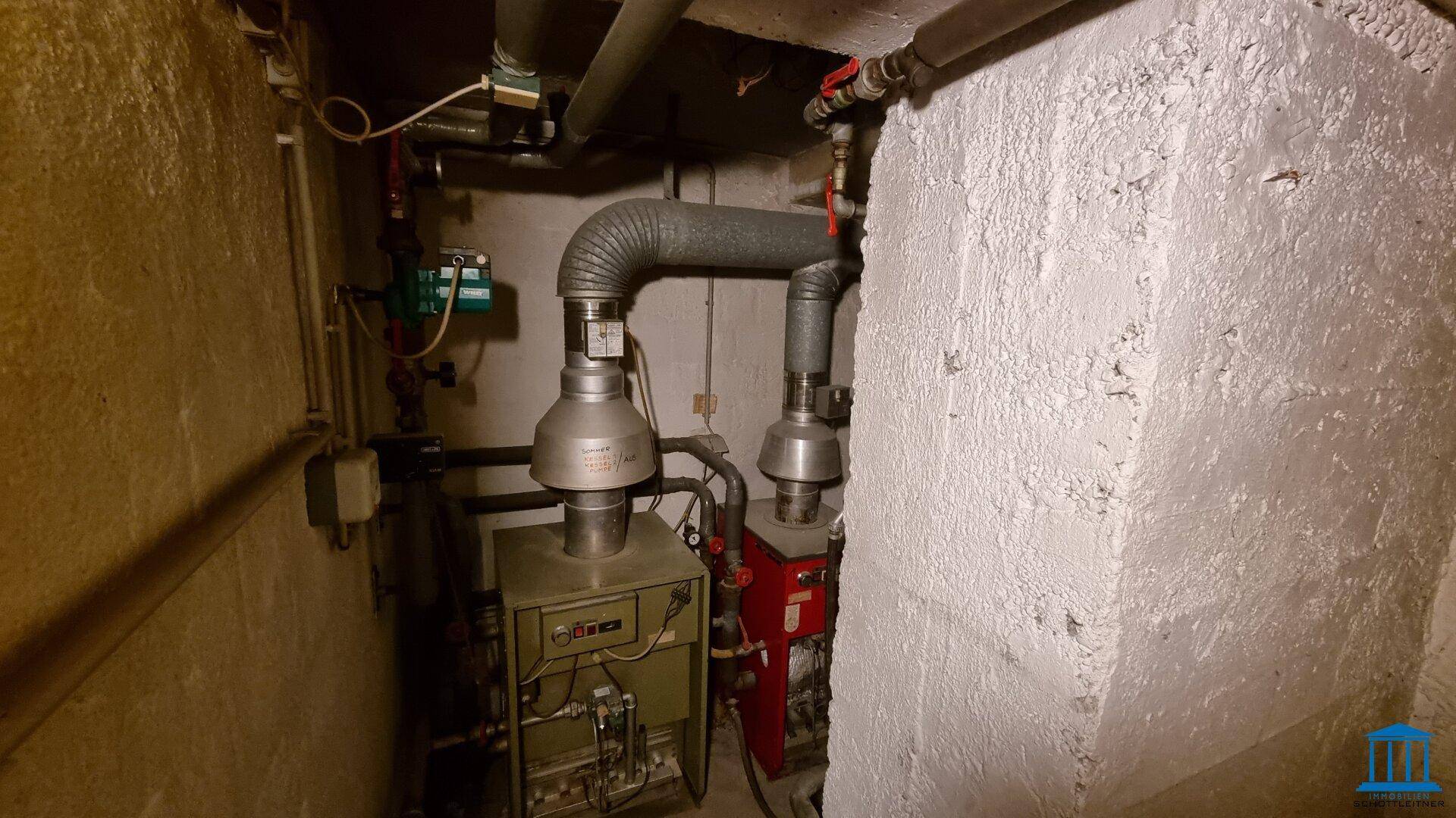Heizungsraum im Keller mit älteren Heizkesseln und sichtbaren Rohren, funktional und gut zugänglich.
