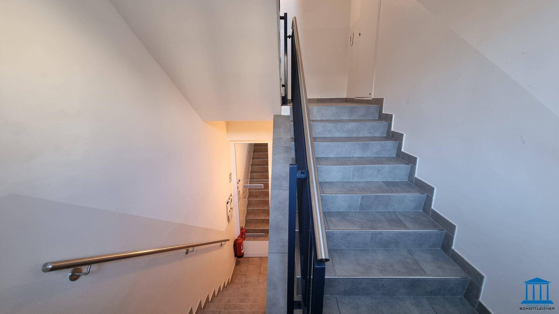Treppenhaus mit Fliesenstufen und Metallgeländer, das die verschiedenen Etagen verbindet.