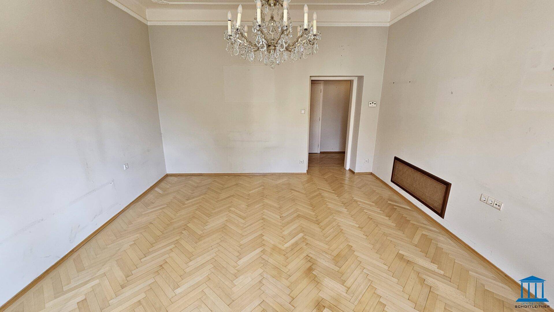 Geräumiges Wohnzimmer mit Fischgrätparkett und hohen Decken, bereit für individuelle Gestaltung.