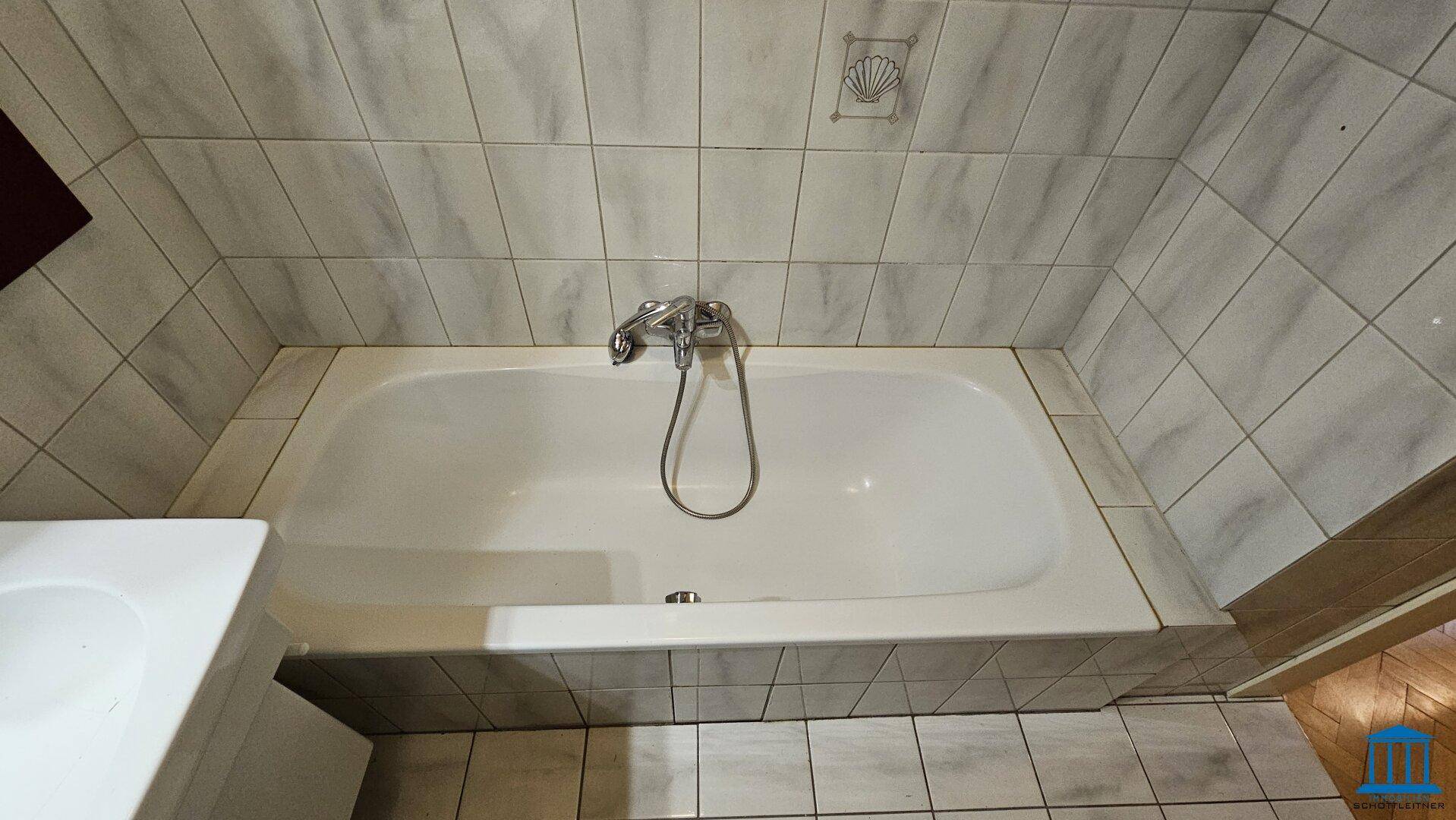 Badewanne in einem gefliesten Badezimmer, bereit für Entspannung nach einem langen Tag.