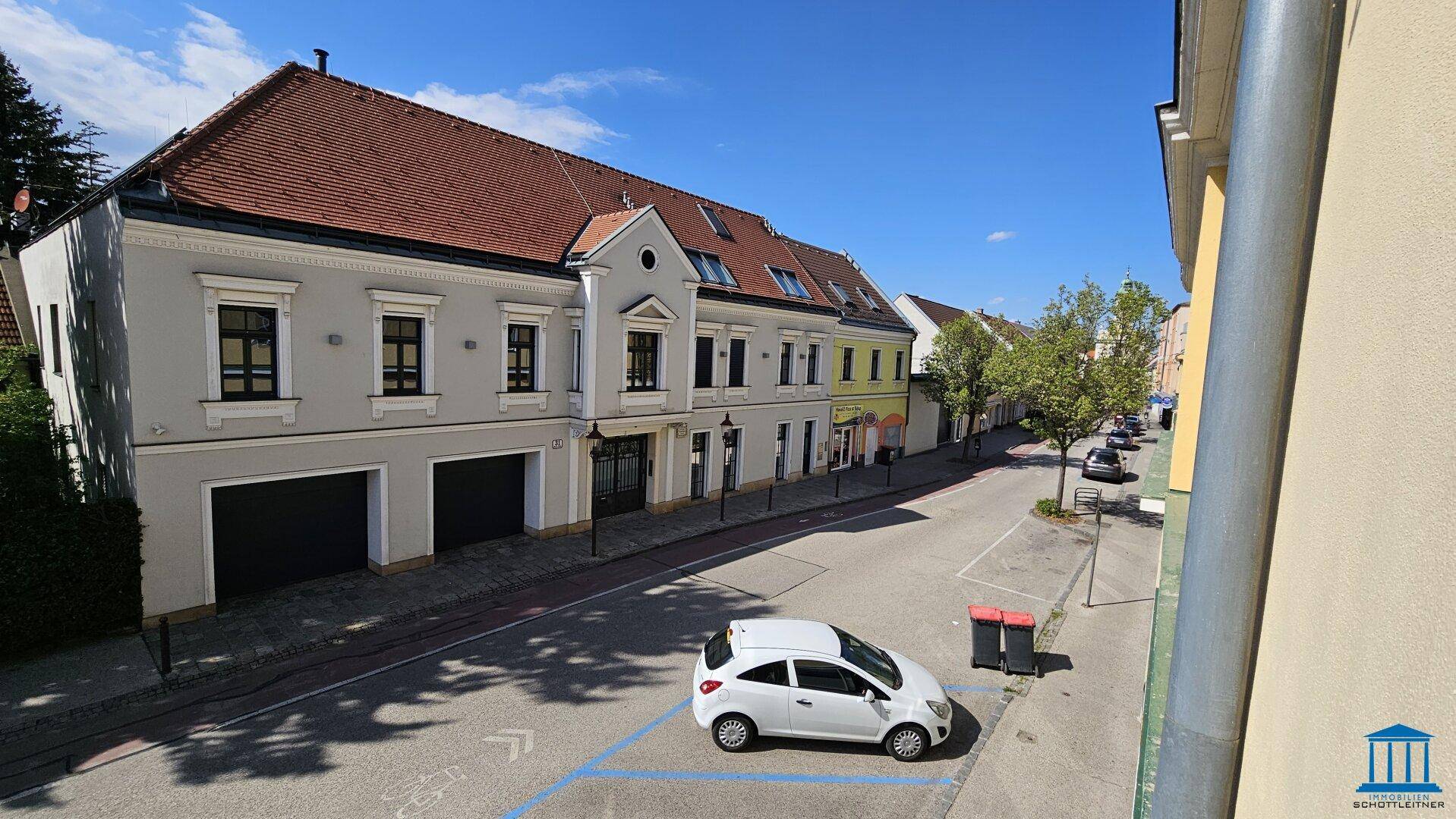 Blick auf eine ruhige Wohnstraße mit geparkten Autos und Gebäuden mit traditioneller Architektur.