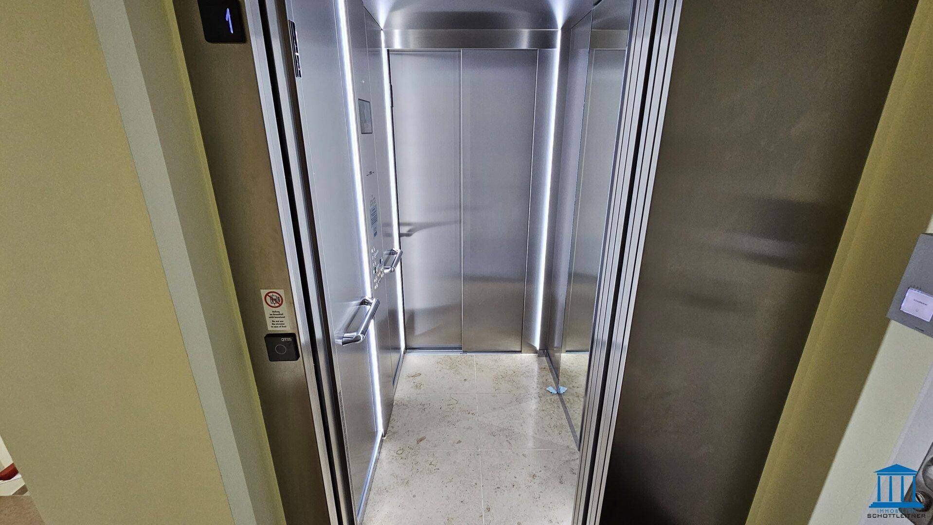 Moderner Aufzug mit Edelstahloberflächen und integrierter Beleuchtung im Innenraum des Gebäudes.