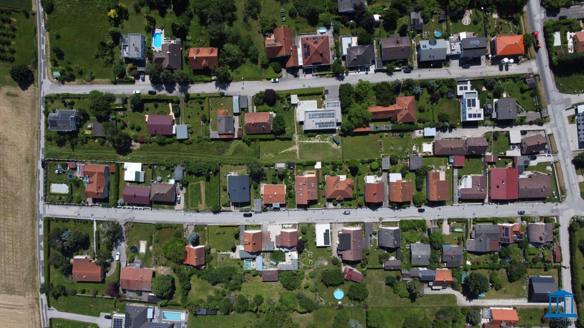 Weitwinkel-Luftaufnahme eines großen Wohngebiets mit vielen Häusern, Gärten und Straßen.