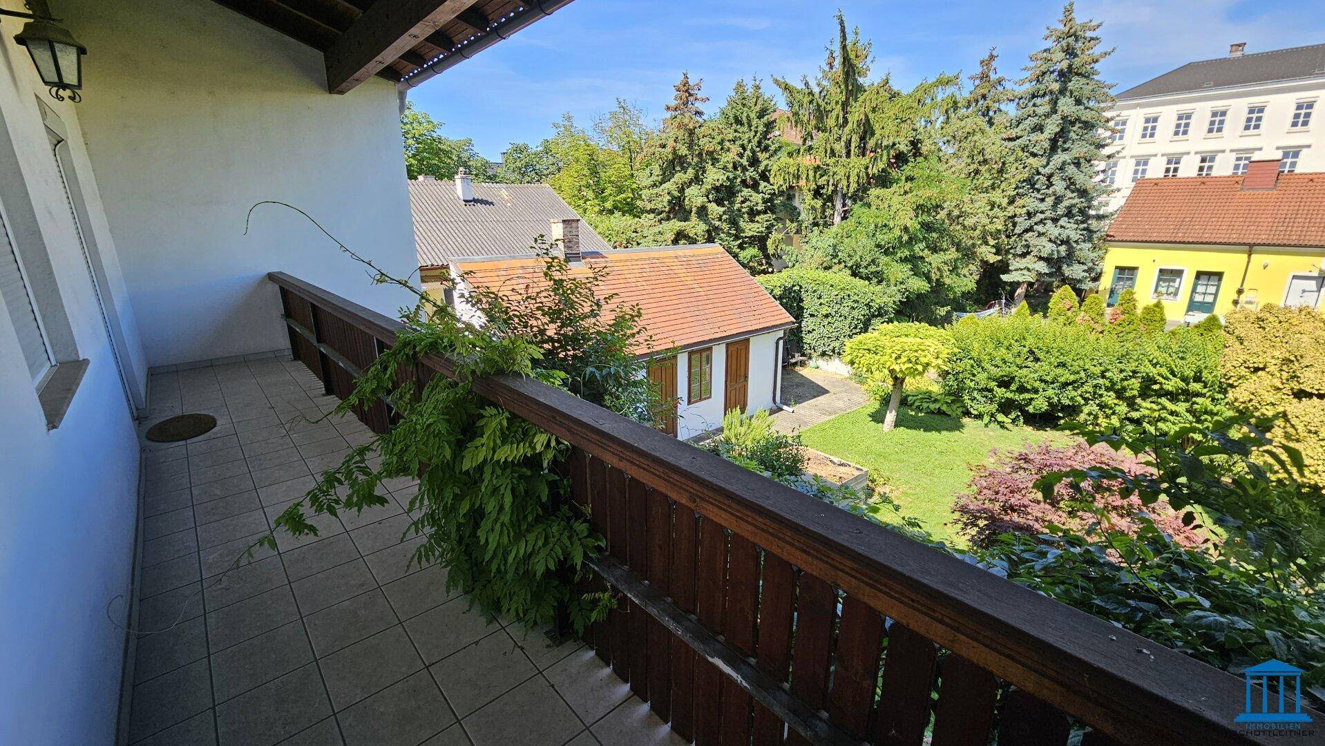 Geräumiger Balkon mit Blick auf den weitläufigen Garten und die umliegende Bebauung.