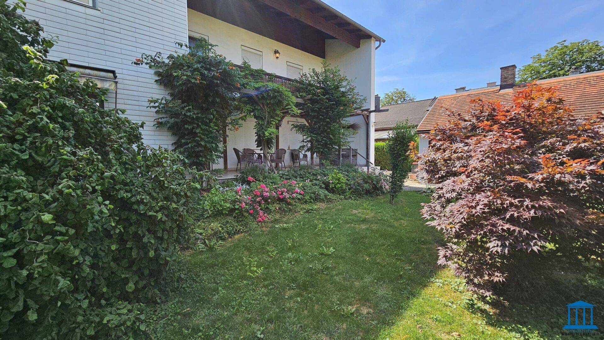 Gepflegter Gartenbereich mit üppiger Bepflanzung und einer überdachten Terrasse am Haus.