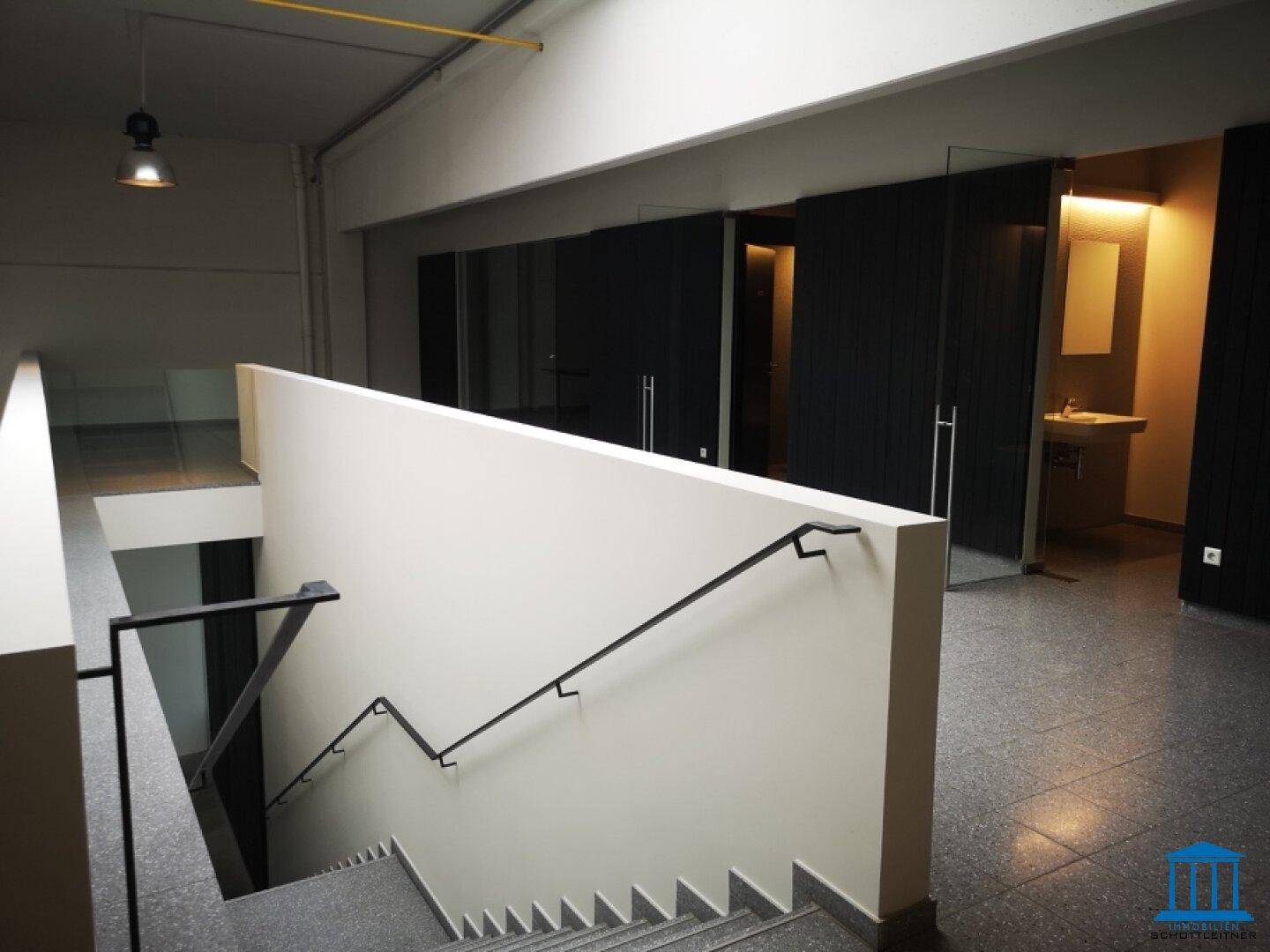 Treppenhaus mit Terrazzoboden und Zugang zu modernen Sanitärbereichen oder Büros.