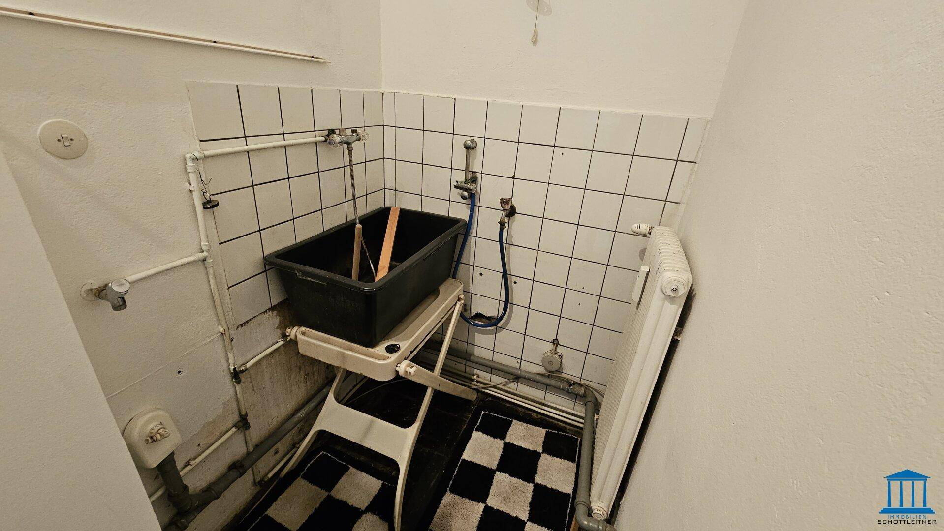 Funktionaler Hauswirtschaftsraum mit gefliesten Wänden, einem Waschbecken und einem Heizkörper.