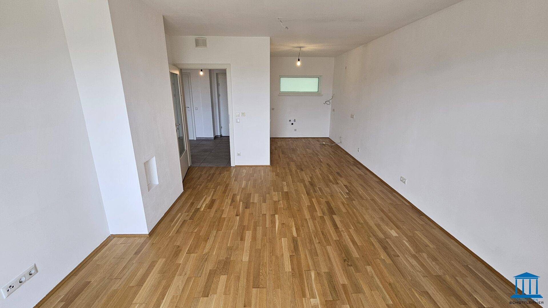 Geräumiges, leeres Zimmer mit Parkettboden und weiß gestrichenen Wänden, bereit zur Einrichtung.