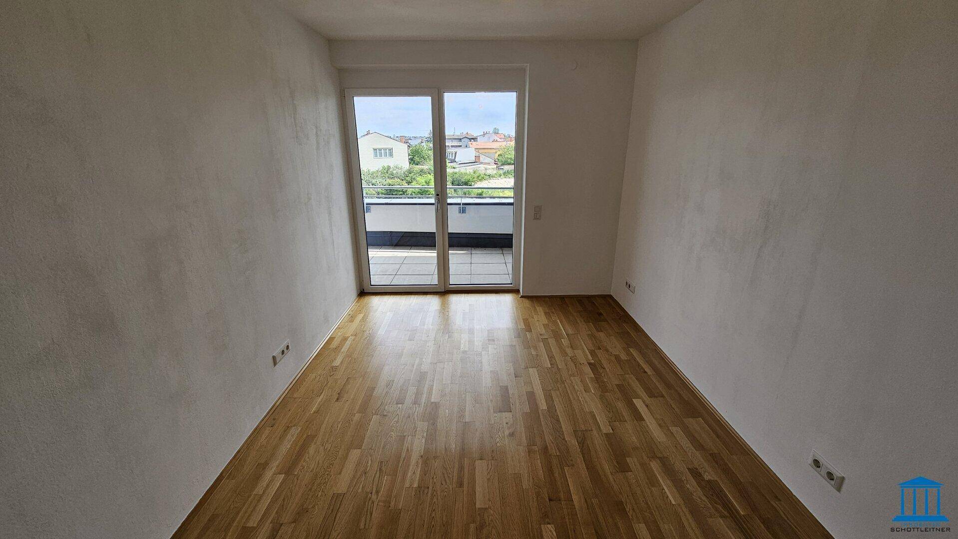 Helles Schlafzimmer mit Parkettboden und direktem Zugang zum Außenbereich.
