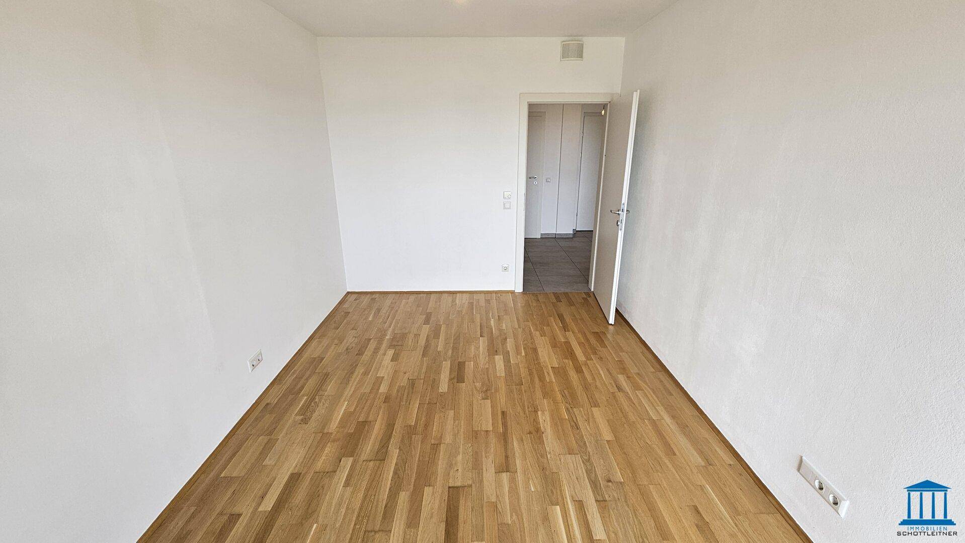 Leeres Zimmer mit Parkettboden und weiß gestrichenen Wänden, ideal als Schlafzimmer.